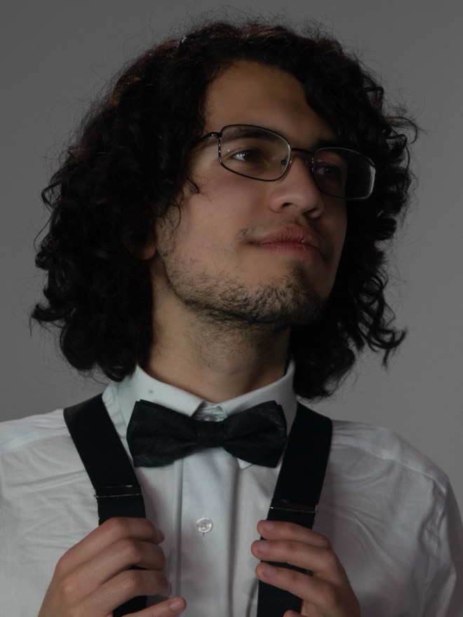 Victor looking off to the side, holding his suspenders