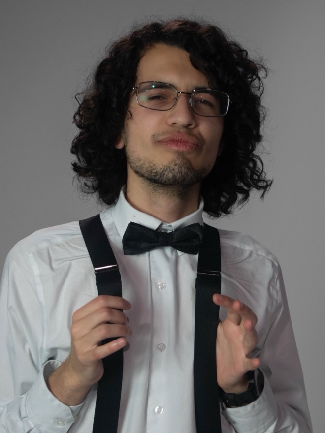 Victor looking at the camera with a slight smirk, thumbs in his suspenders