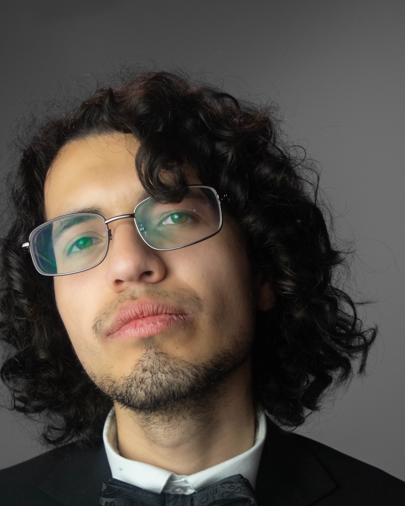 Portrait of Victor Puente, chin raised, showing his curly hair